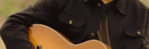 Jai Uttal playing guitar on a beach